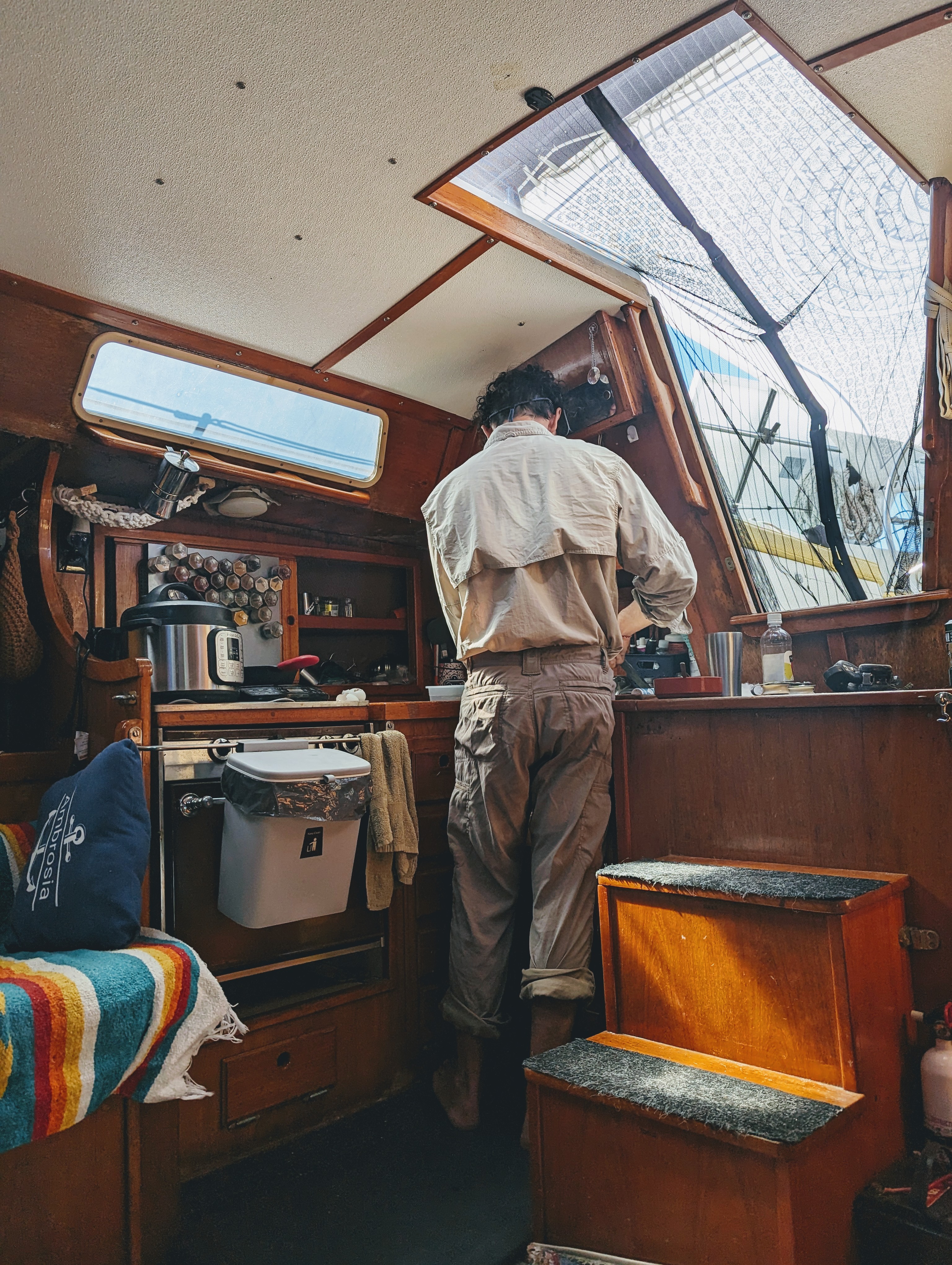 Person cooking in the cozy wooden galley of a sailboat